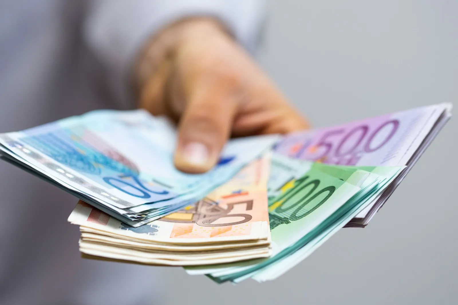 Mann hält diverse Euro-Banknoten in der Hand